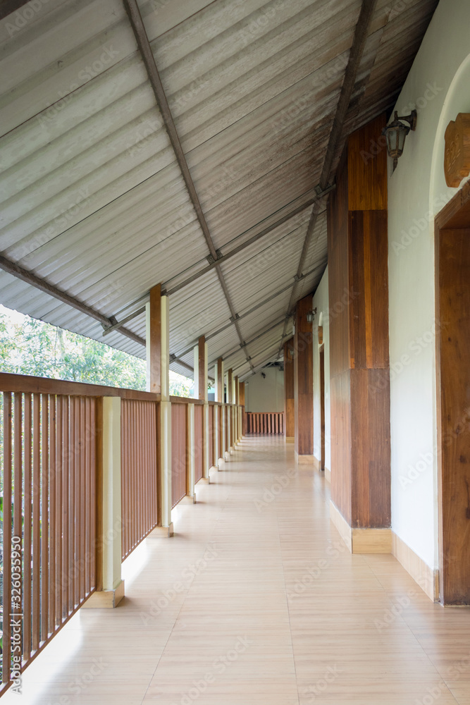 Balcony corridor with slanting tin roof, ceramic floor and wooden railing
