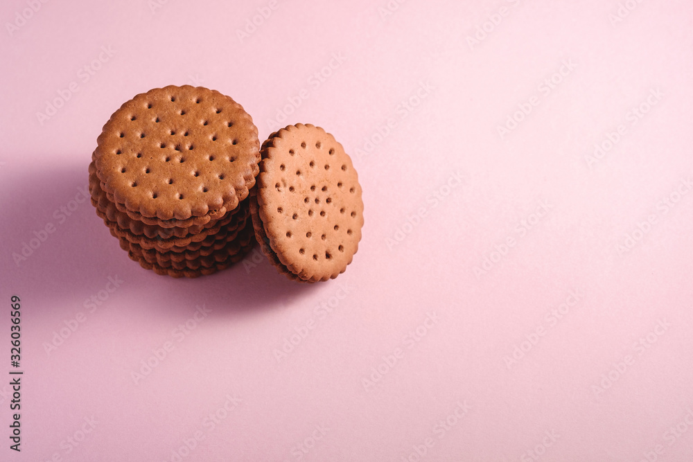 Chocolate sandwich cookie with cream, sweet stacked food from store, on pink pastel background, angle view Chocolate sandwich cookie with cream, sweet stacked food from store, on pink pastel background, angle view