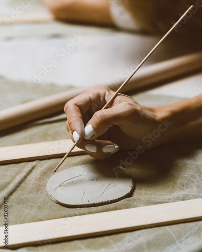 Woman making pattern on ceramic plate  drawing. Creative hobby concept. Earn extra money