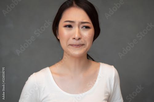 crying sad and unhappy asian girl; portrait of frustrated depressed Chinese or east asian woman cries out; young adult Chinese asian woman model
