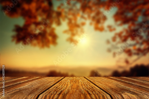 Autumn Background with Empty Wooden Table on Foreground. Sunny Fall Day with Sun and Orange Leaves on Tree.