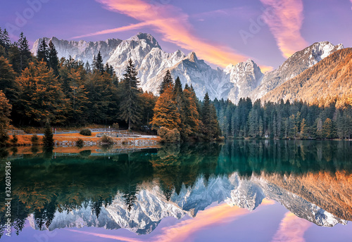Fototapeta Naklejka Na Ścianę i Meble -  Impressive Autumn landscape during sunset.  The Fusine Lake in front of the Mongart under sunlight. Amazing sunny day on the mountain lake. concept of an ideal resting place. Creative image.