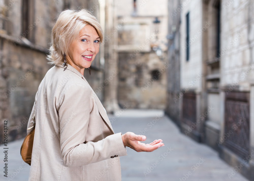 Fototapeta premium Cheerful mature female is walking in classic jacket