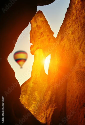 Wallpaper Mural The relief of the rocks and the rays of the sun between the rocks, in the background is an airy colorful balloon in the sky. The atmosphere of relaxation and travel. Torontodigital.ca