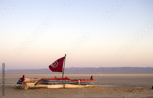 Sunrise on Sahara beach - boat with Tunisian flag