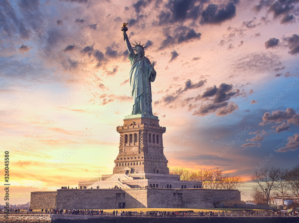 famous statue of  liberty and dramatic sky at sunset with orange colors - obrazy, fototapety, plakaty 