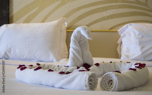 Swan made from towels lying on the bed in hotel apartament. 