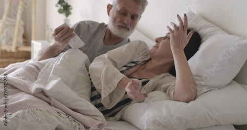 Furious Caucasian senior man taking away wife's smartphone in bed. Husband looking angrily at brunette woman chatting in social media in the morning. Betrayal, love affair. Cinema 4k ProRes HQ. photo