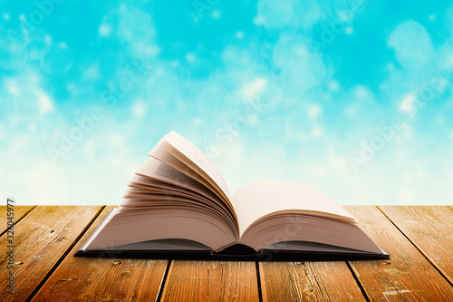 Open Book on Wooden Background with Blurred Blue Backdrop