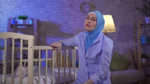 tired portrait Muslim young woman is a mother by the bed in the nursery photo