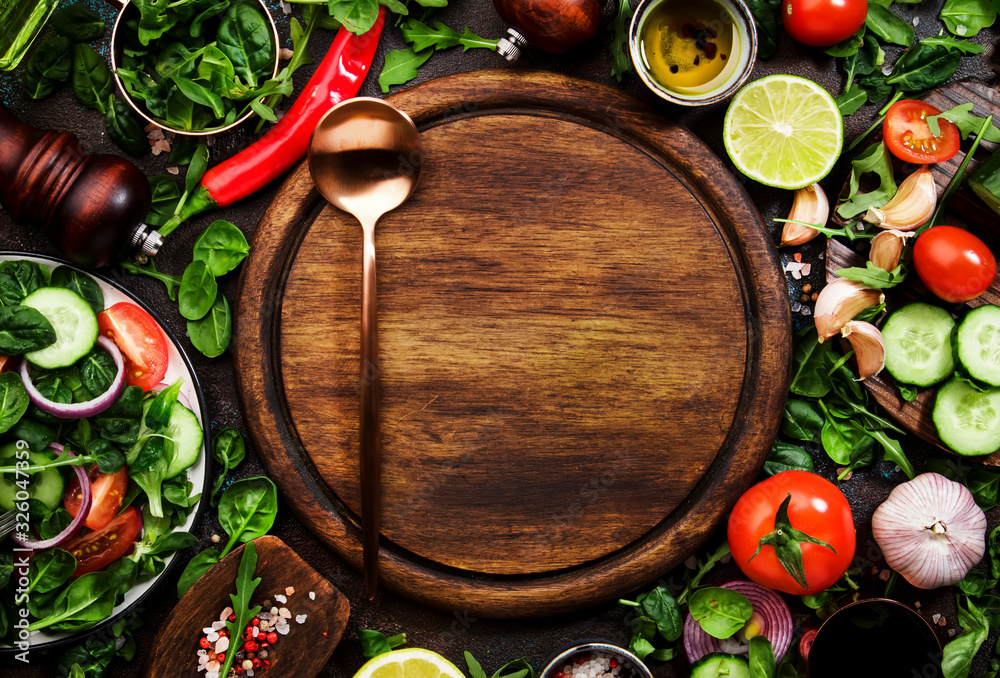 Healthy vegan ingredients layout. Flat-lay of green herbs, tomatoes, cucumbers, spices and oil on brown kitchen table with wooden board. Top view, copy space. Vegetarian, raw, clean eating concept Healthy vegan ingredients layout. Flat-lay of green herbs, tomatoes, cucumbers, spices and oil on brown kitchen table with wooden board. Top view, copy space. Vegetarian, raw, clean eating concept