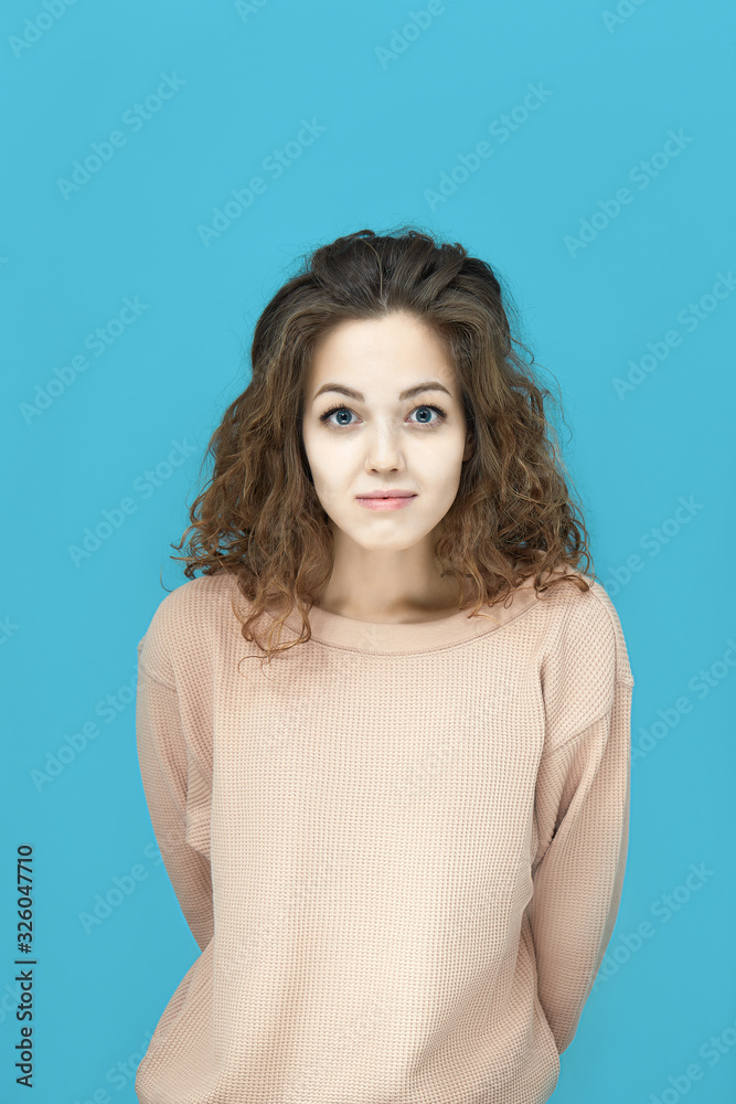 Portrait of a young beautiful woman wearing sweatshirt looking at you coquettishly isolated over blue background Portrait of a young beautiful woman wearing sweatshirt looking at you coquettishly isolated over blue background