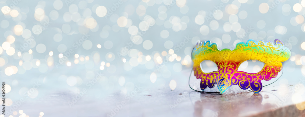 Venetian or Brazilian carnival.Bright multicolored mask on a shiny background with lights and bokeh.holiday.Carnival outfit.Celebration.Banner.Flat lay.Top view.Copyspace