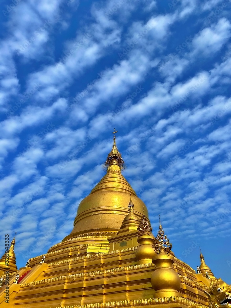 Fototapeta premium The golden pagoda under the blue sky with cloud at Kuthodaw Pagoda, Mandalay, Myanmar