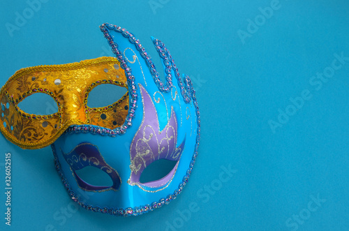 two carnival masquerade masks purple and yellow on a blue background copyspace.