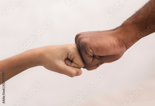 Family Unity. Fist bump of black man and little boy © Prostock-studio