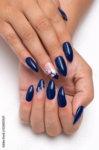  Dark blue manicure on sharp long nails with orchids and white, blue crystals on the ringless fingers. Indigo manicure.