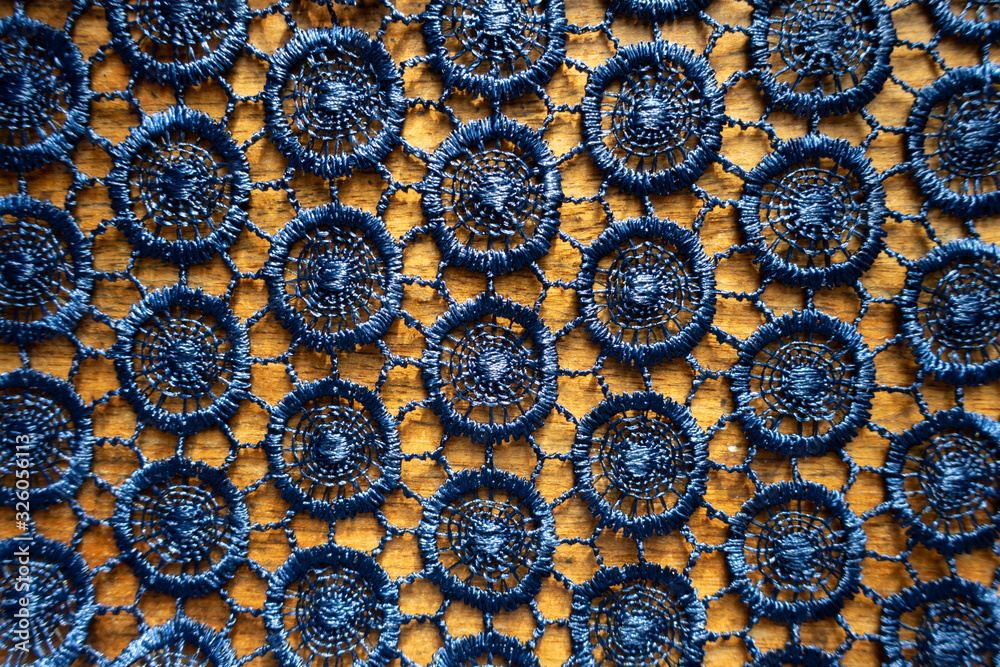 Surface of dark blue crochet lacy fabric on wood from above