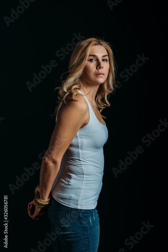 Victim with tied hands looking at camera isolated on black