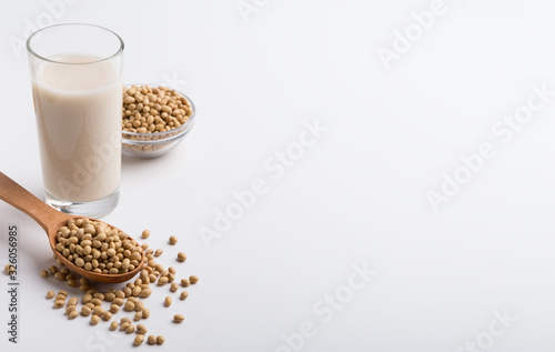 Soy milk in glass, beans in bowl and wooden spoon