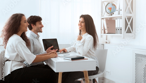 Young travel agent working with clients and discussing tour