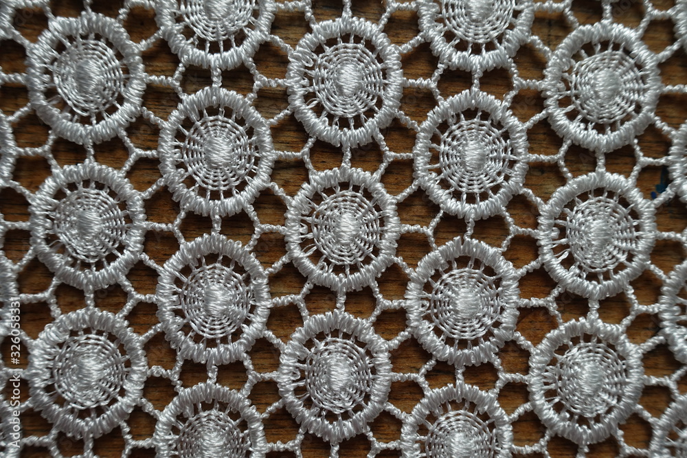 Close shot of ivory white crochet lacy fabric on wood from above Close shot of ivory white crochet lacy fabric on wood from above