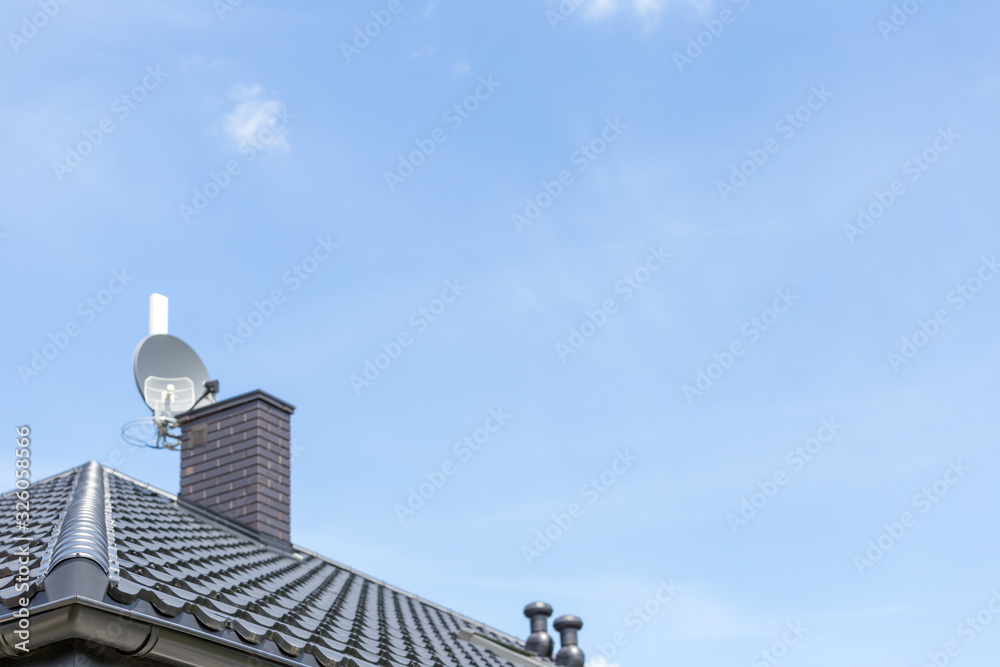 roof of the new modern house with gutter, ventilation chimney and satellite dish under blue sky