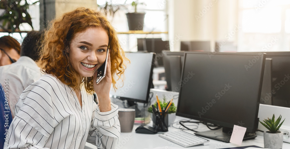 Close up of ginger girl talking by phone in office