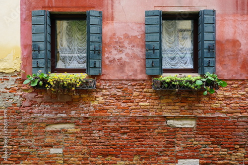 Green shutters and windowboxes on a pink brick wall in Venice, Italy photo
