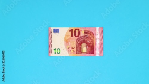 Rolled ten euro banknote appear and unroll on blue background - Stop motion 