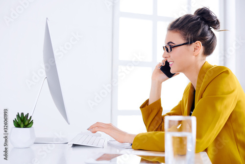 Young business woman talking on the phone while using desktop photo