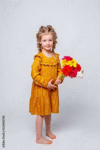 portrait of a smiling child a blonde girl with a bouquet of flowers isolated on a white background