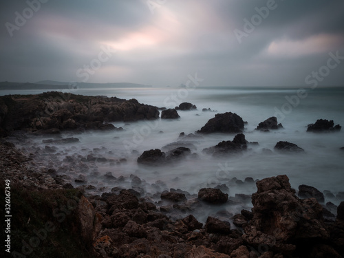 Wallpaper of rocky beach landscape at sunset on a cloudy day