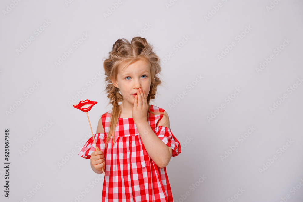 Funny smiling baby girl summer dress on white background . Baby girl with a lip accessory on a stick. Funny smiling baby girl summer dress on white background . Baby girl with a lip accessory on a stick.