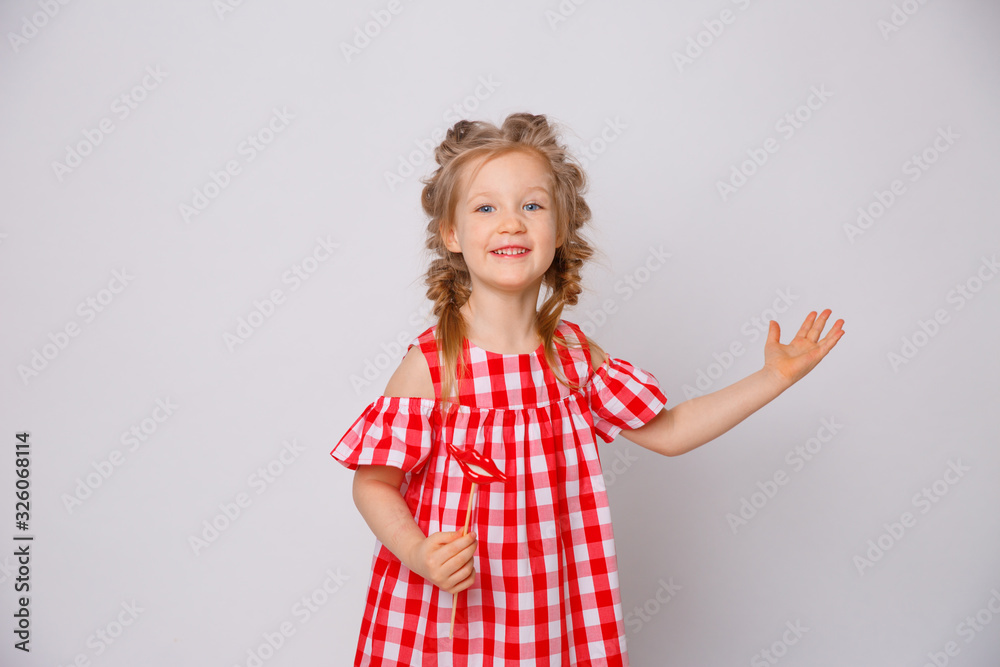 Funny smiling baby girl summer dress on white background . Baby girl with a lip accessory on a stick. Funny smiling baby girl summer dress on white background . Baby girl with a lip accessory on a stick.