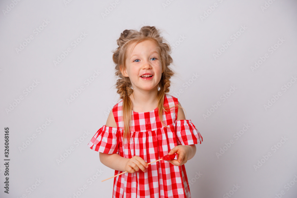 Funny smiling baby girl summer dress on white background . Baby girl with a lip accessory on a stick. Funny smiling baby girl summer dress on white background . Baby girl with a lip accessory on a stick.