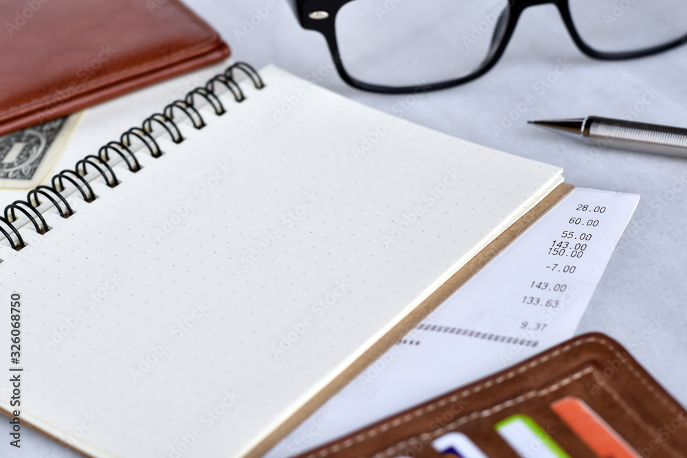 Close-up view, Blank notebook for daily expenses with wallet, bill, pencil and glasses is elements. Close-up view, Blank notebook for daily expenses with wallet, bill, pencil and glasses is elements.