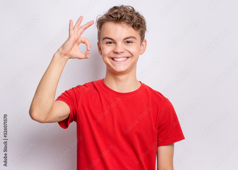 Portrait of teen boy making Ok gesture on grey background. Handsome caucasian young teenager smiling and giving OK sign. Happy cute child showing okay. Portrait of teen boy making Ok gesture on grey background. Handsome caucasian young teenager smiling and giving OK sign. Happy cute child showing okay.