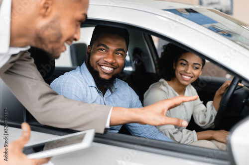 Joyful Couple Buying Car Talking With Salesman In Dealership Store © Prostock-studio
