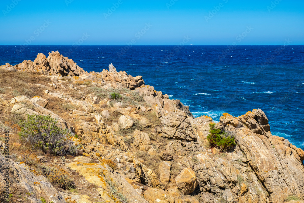 Panoramic view of Capo Figari cape rocks and seashore of Spiaggia di Cala Spada beach at the Tyrrhenian Sea coast in Golfo Aranci, Sardinia, Italy