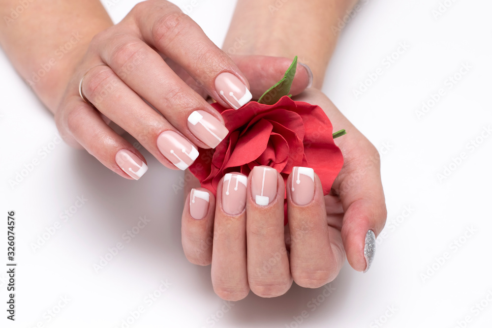 Wedding French manicure with a red rose in hands on short square nails. Classic white manicure. Wedding French manicure with a red rose in hands on short square nails. Classic white manicure.