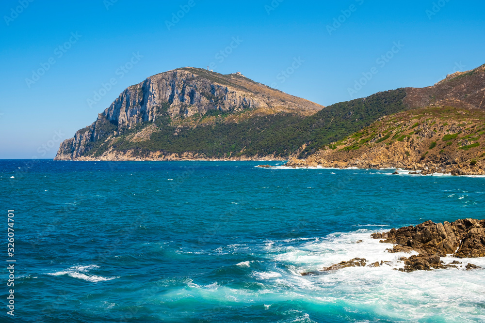 Panoramic view of Capo Figari cape cliffs and rocks with Monte Ruju mount at the Tyrrhenian Sea coast in Golfo Aranci, Sardinia, Italy