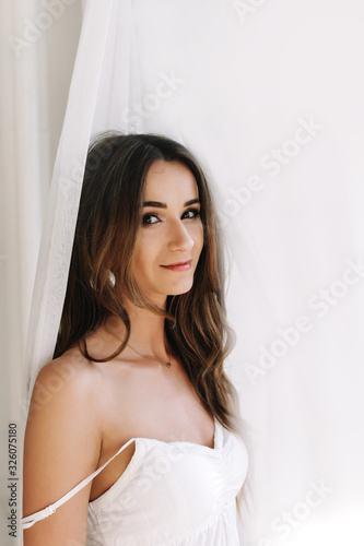 Portrait of a young beautiful woman. Bride in elegant classic wedding dress. Morning of the bride. Wedding preparations.
