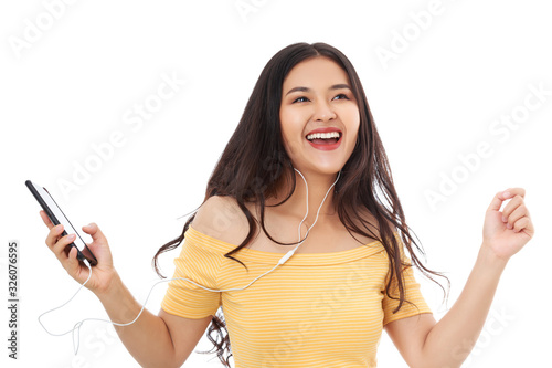 Young attractive Asian woman listening to the music online in smart phone also singing and dancing, isolated on white.