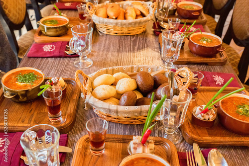 Table with portions of tasty borsch, lard and alcohol drink on wooden background