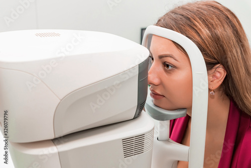 Measuring young woman's eye pressure with tonometer photo