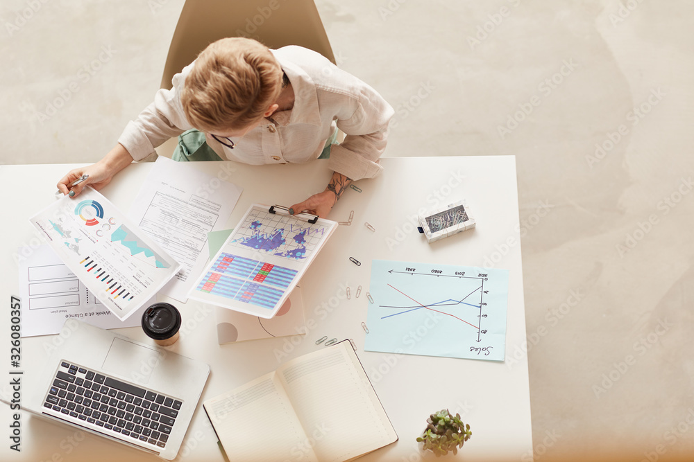 Above view background of modern businesswoman holding data charts while sitting at table, copy space Above view background of modern businesswoman holding data charts while sitting at table, copy space