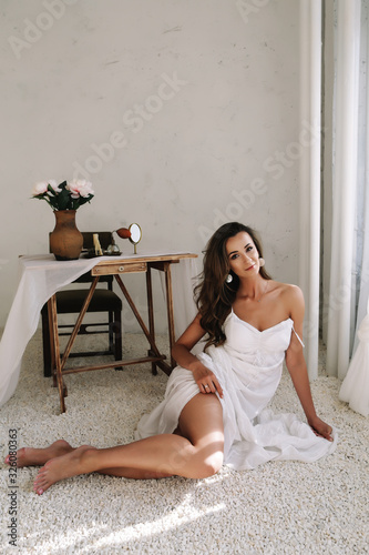 Portrait of a young beautiful woman. Bride in elegant classic wedding dress. Morning of the bride. Wedding preparations.