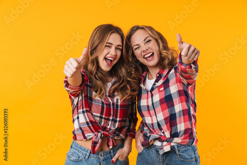 Image of two young beautiful girls smiling and gesturing thumbs up