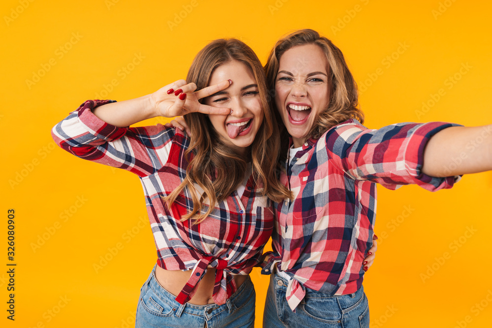 Image of two young girls smiling and hugging while taking selfie photo Image of two young girls smiling and hugging while taking selfie photo